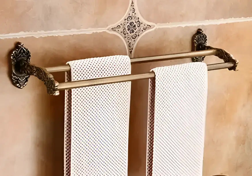 Antique bronze carved aluminum double towel rack with ornate scrollwork holding two off-white textured towels