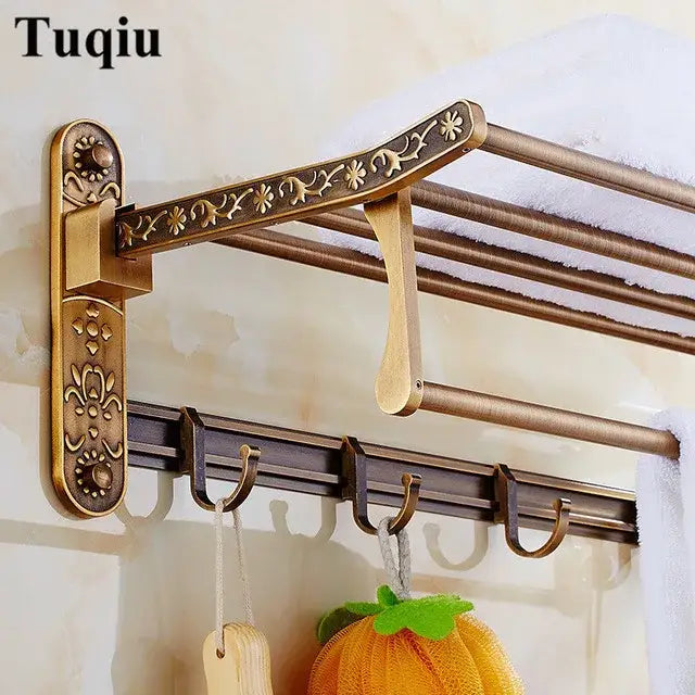 Antique brass-finished wall-mounted towel rack with ornate floral detailing and matching hook bar in bathroom accessories set