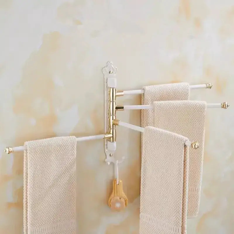 White and gold carved swivel towel rack with three extendable arms holding beige towels for bathroom use
