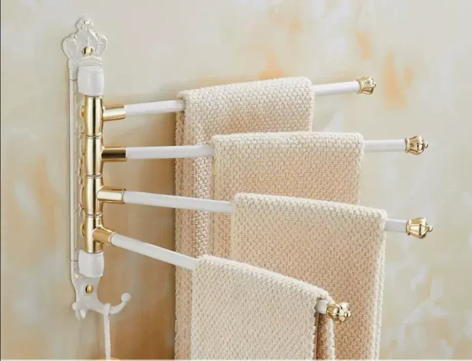 Gold and white ornate antique carved swivel towel rack with four arms holding cream textured towels for bathroom use