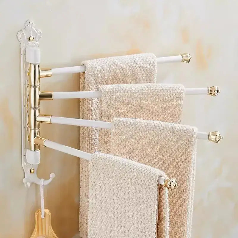 White and gold ornate antique carved swivel towel rack with four rotating arms holding textured beige towels wall mounted