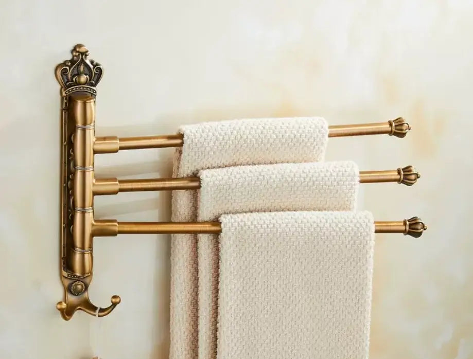 Decorbites antique carved swivel towel rack in brass with ornate crown top and three bars holding cream towels