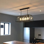 Black metal-framed clear glass pendant light with 4 exposed filament bulbs for dining room and island lighting
