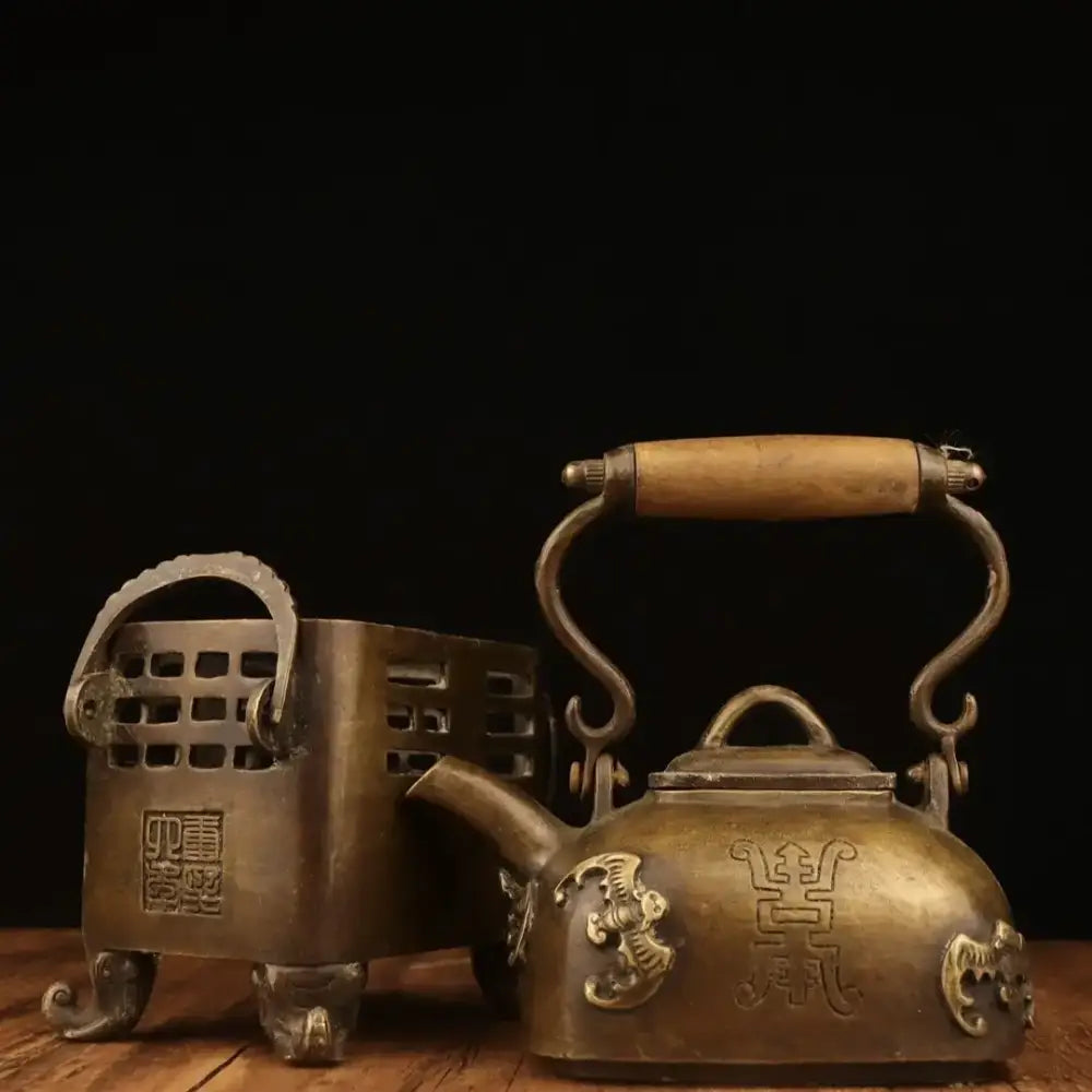 Antique brass tea kettle with ornate dragon motifs and wooden handle on matching perforated stand for warm wine pots