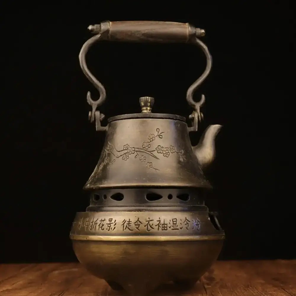 Antique bronze warm wine pot with engraved cherry blossoms, Chinese characters, wooden handle, and ornate metal spout from DecorBites™