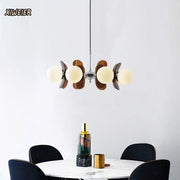 Modern pendant light featuring warm frosted glass globes and dark wood leaf accents in decorbites antique style chandelier