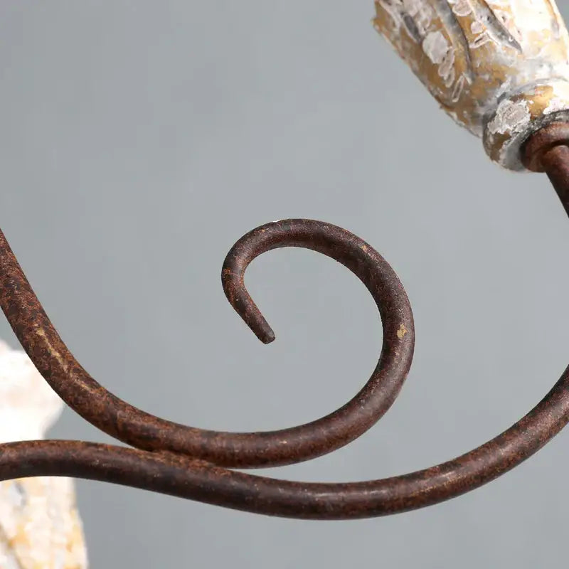 Rusty iron scrollwork with aged patina detail on decorbites antique white wooden chandelier elegant french rustic lighting