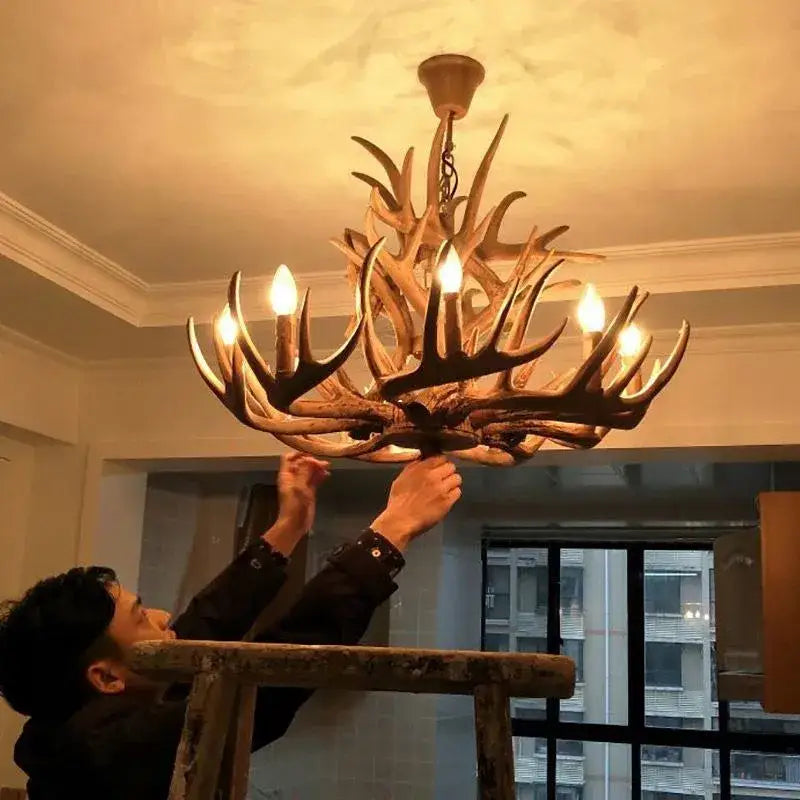 DecorBites antler chandelier with warm-toned natural wood finish and multiple lit bulbs for rustic indoor decor