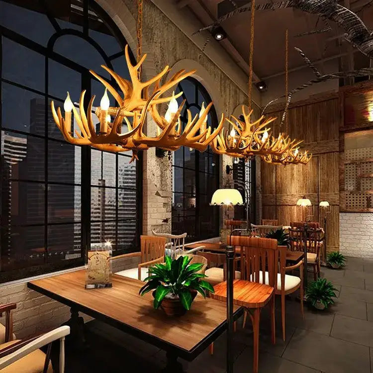 Golden decorbites antler chandelier with multiple lit bulbs made of resin horns for rustic indoor decor hanging from ceiling