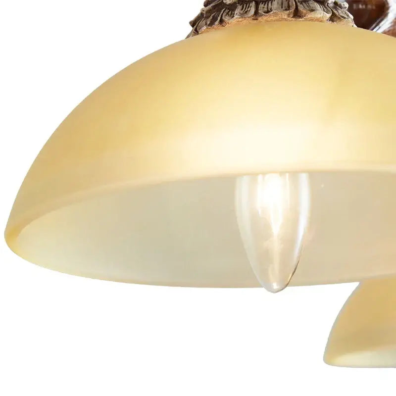 Cream-colored translucent glass lampshade with textured bronze top on decorbites antler resin chandelier pendant light