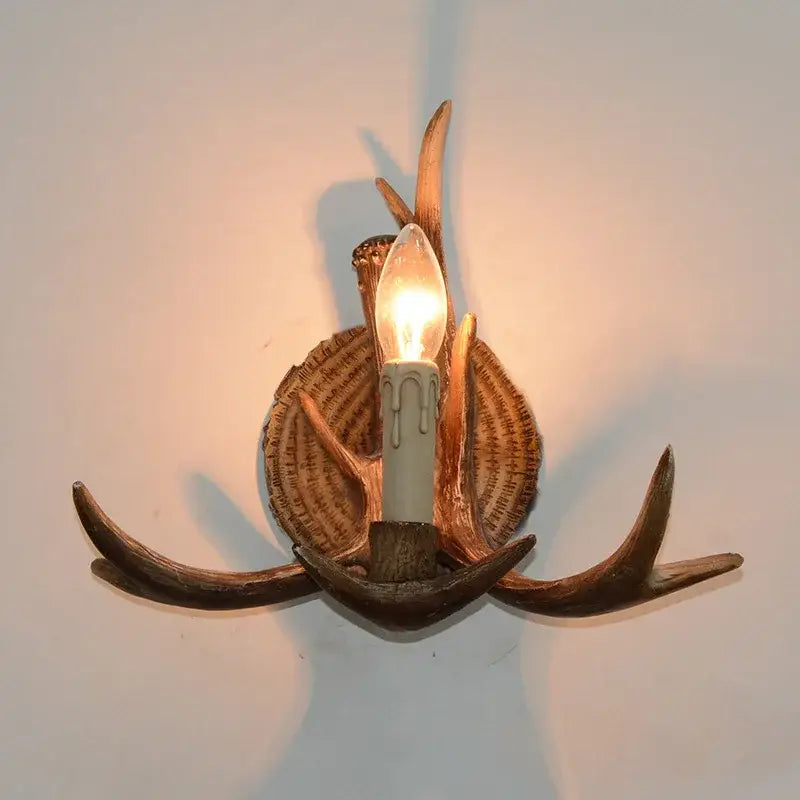 Decorbites antler resin wall lamp with dark brown antlers and warm glowing bulb on rustic wooden base for living room