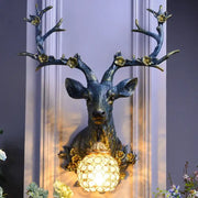 Antique bronze decorbites antler wall lamp featuring a resin deer head and faceted crystal globe light with gold accents