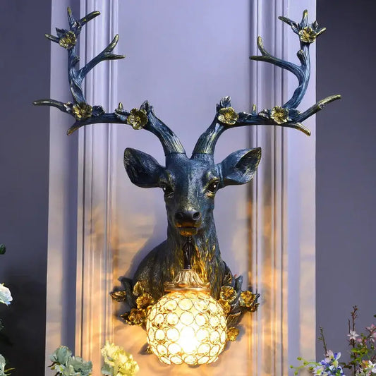Antique bronze decorbites antler wall lamp featuring a resin deer head and faceted crystal globe light with gold accents