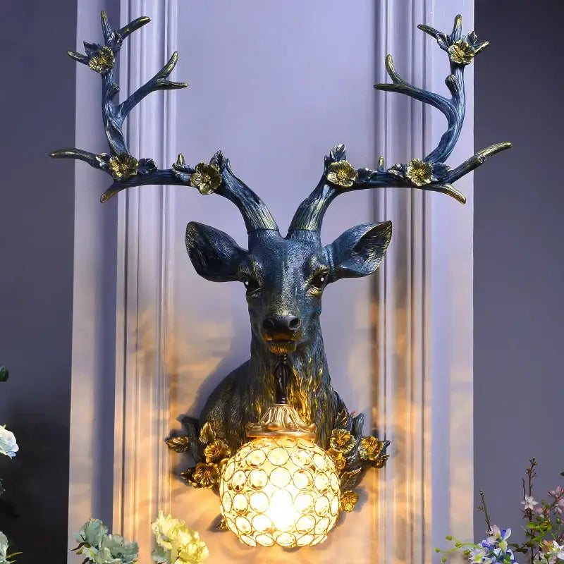 Antique bronze decorbites antler wall lamp featuring a resin deer head and faceted crystal globe light with gold accents