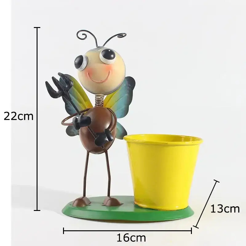 A whimsical metal bee figurine with yellow and blue wings beside a bright yellow pot in the DecorBites ants gardener vase
