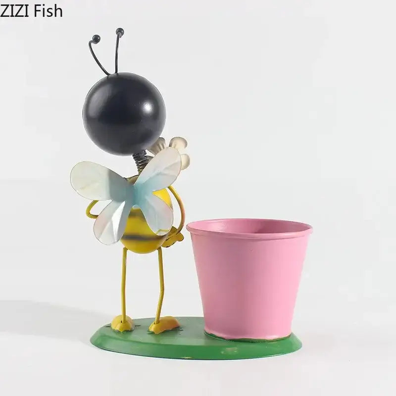 Yellow and black metal bee figurine with translucent wings beside a pink DecorBites™ ants gardener vase for room decor