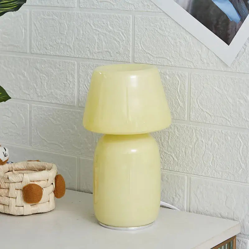 A sleek pale yellow decorbites apollo mushroom glass table lamp with smooth rounded design for bedside lighting