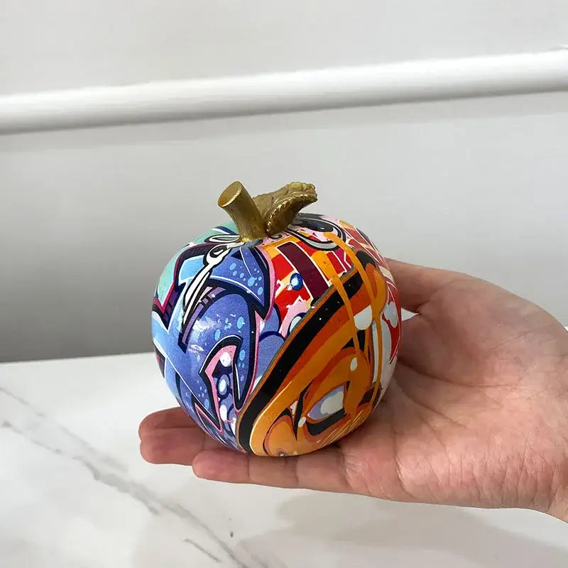 A vibrant hand-painted decorbites apple figurines art pumpkin sculpture with gold stem in blues oranges reds and black