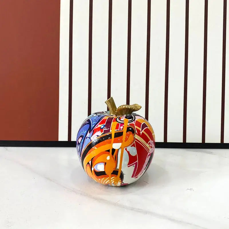 A vibrant glossy decorbites apple figurines art ornament with gold stem and colorful graffiti design for home office decor