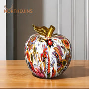 A vibrant decorbites apple resin figure ornament with intricate patterns, glossy finish, and golden stem for decor