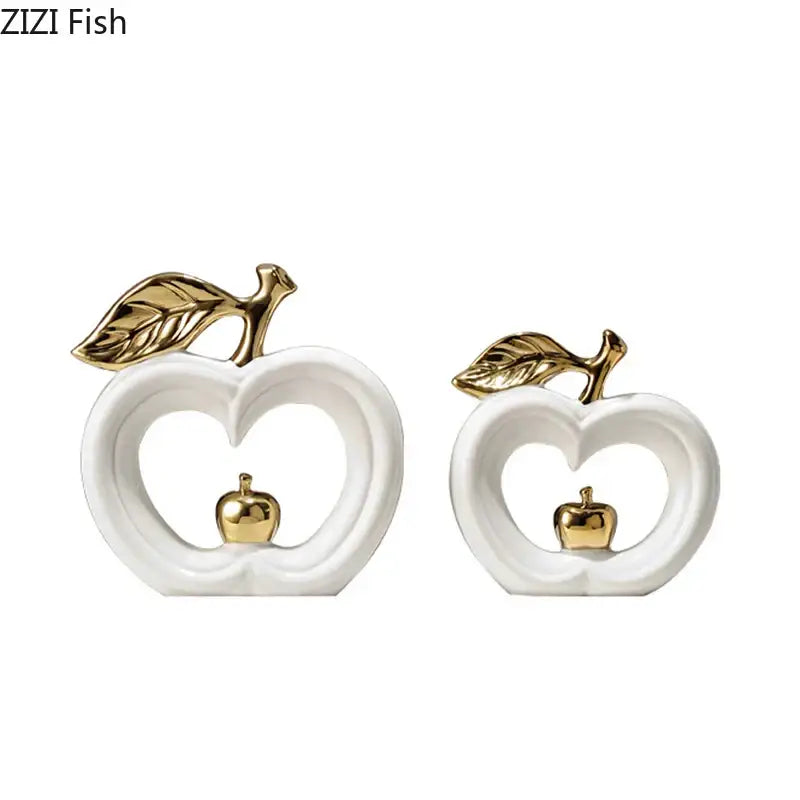 White ceramic decorbites apple sculpture with gold leaf and stem accents featuring a miniature golden apple inside