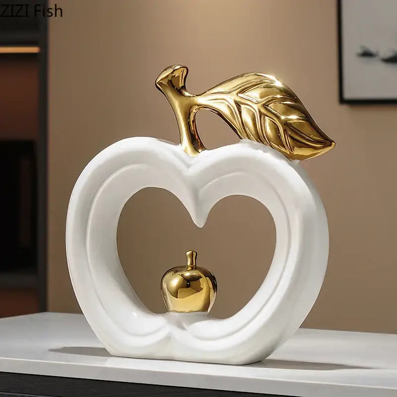 White ceramic decorbites apple sculpture with gold leaf and heart-shaped cutout holding miniature golden apple for decor