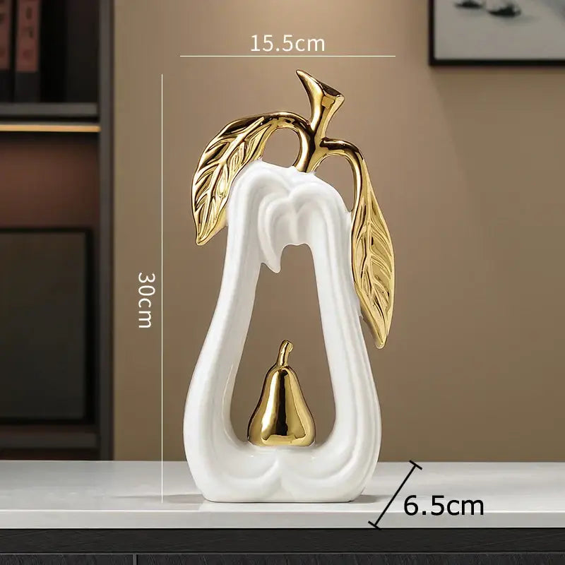 White ceramic pear sculpture with gold leaf and metallic accents as a decorbites apple sculpture for minimalist decor