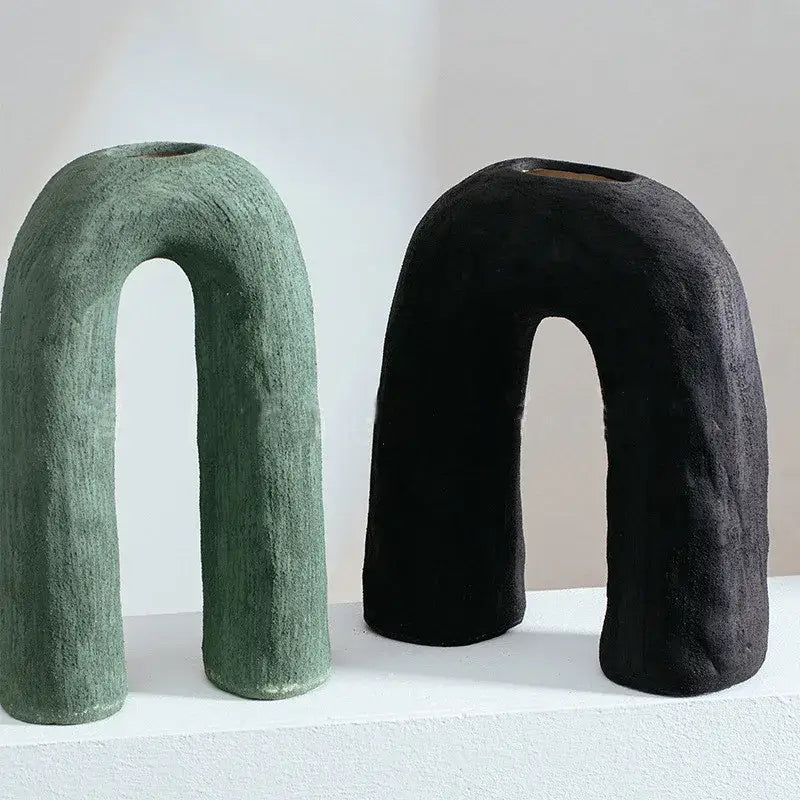 Two decorbites arc ceramic vases in muted green and black with textured matte finish and u-shaped geometric design