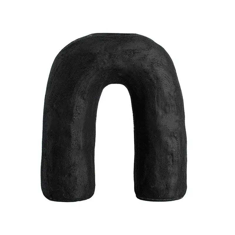 Black u-shaped neck pillow with soft textured fabric paired with decorbites arc ceramic geometric vase