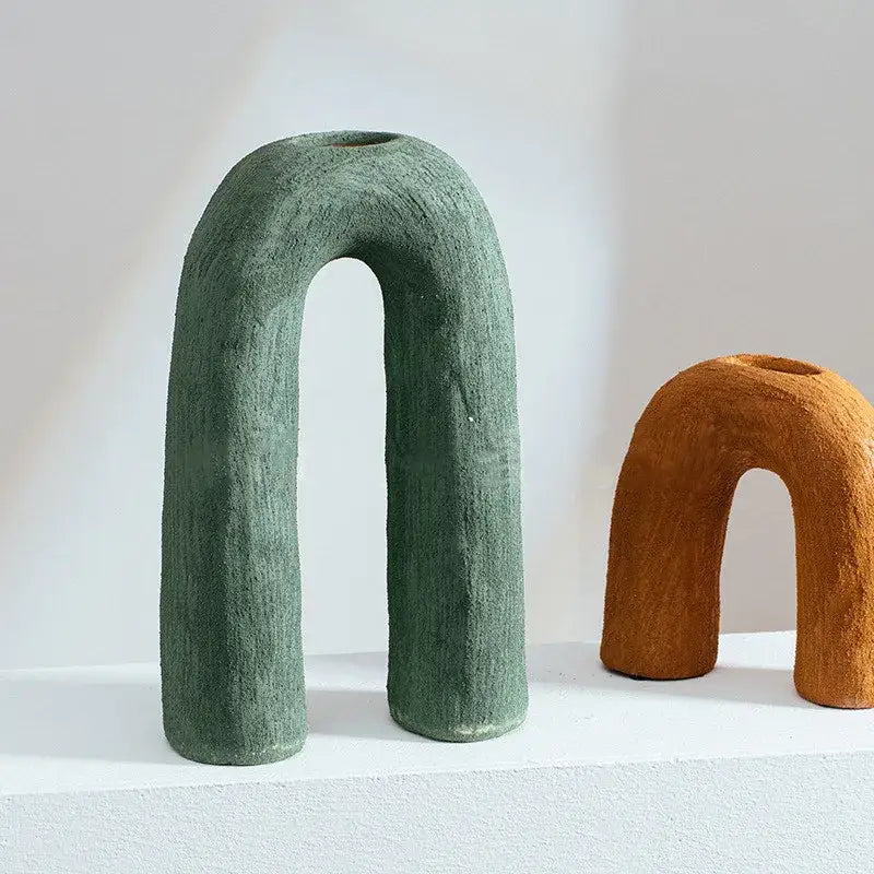 A matte green textured decorbites arc ceramic vase with an arched shape and open top for flower arrangement
