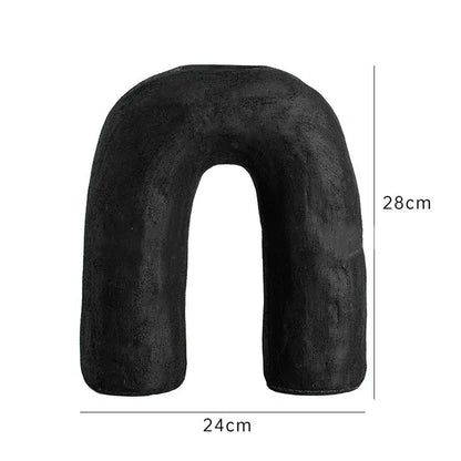 Black plush u-shaped neck pillow 28cm tall 24cm wide shown alongside decorbites arc ceramic vase home decor accessory