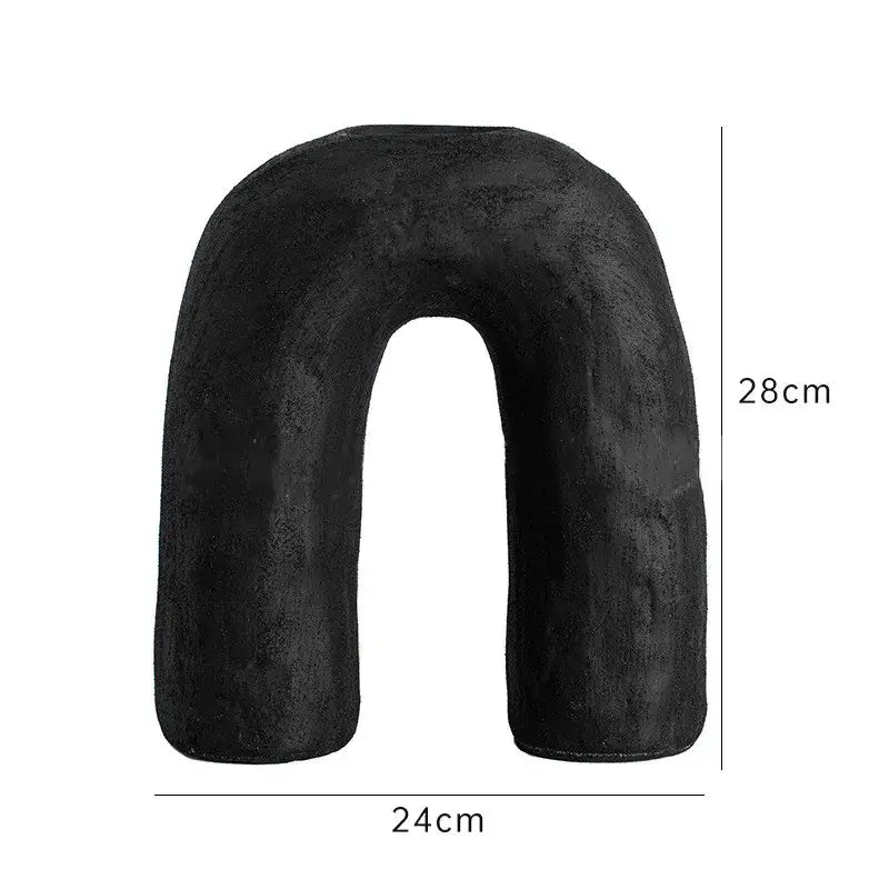 Black plush u-shaped neck pillow 28cm tall 24cm wide shown alongside decorbites arc ceramic vase home decor accessory