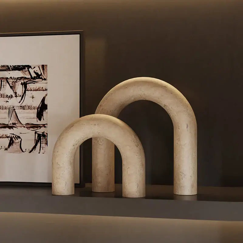 Two beige decorbites archway shape travertine sculptures with smooth textured surface for home decor display