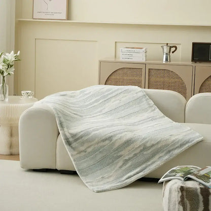 A soft light gray decorbites arctic velvet faux rabbit throw blanket with subtle texture draped over a modern sofa