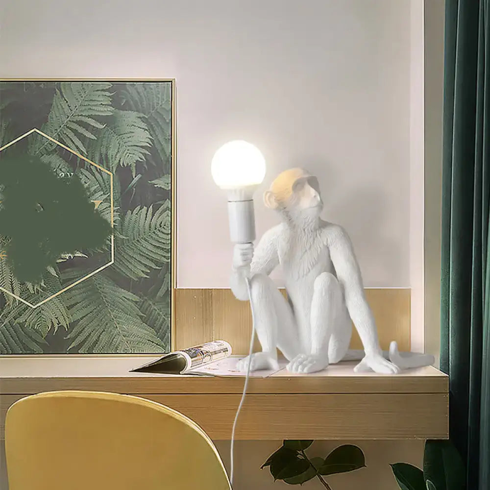 Decorbites art deco white monkey table lamp with shadeless design holding a spherical bulb in resin material