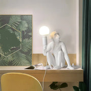 Decorbites art deco white monkey table lamp with shadeless design holding a spherical bulb in resin material