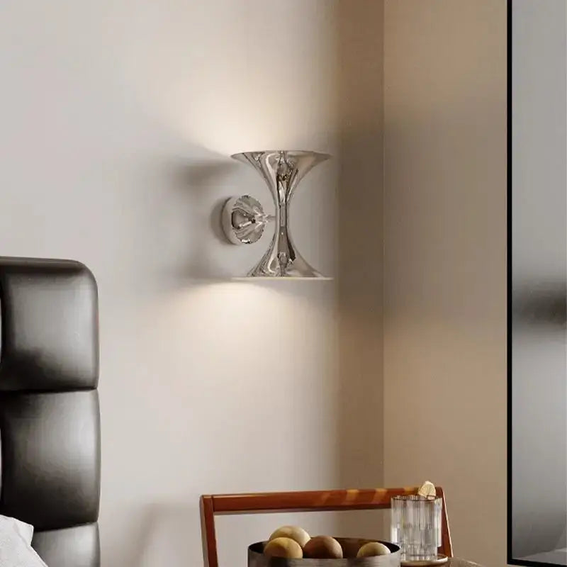 Chrome finished wall lights with sleek sculptural design resembling an inverted hourglass for indoor lighting