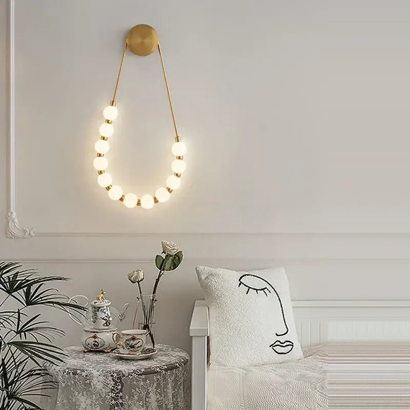 Gold-toned decorbites art deco glass led wall sconce with circular top and glowing spherical bulbs for bedroom lighting
