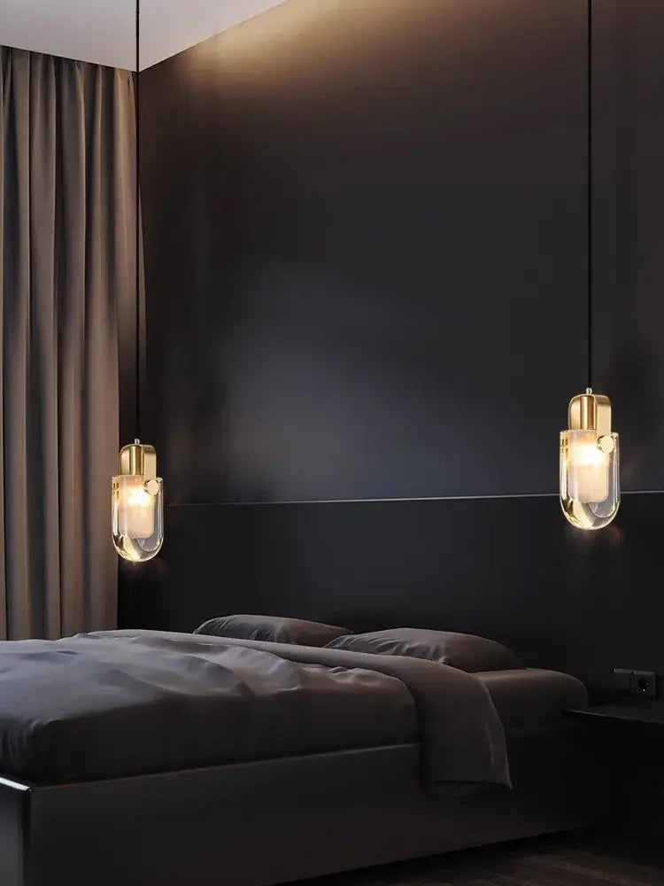 Gold-toned decorbites art deco pendant light with clear glass shades above a dark bed in a minimalist bedroom