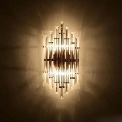 A warm glowing decorbites art deco led wall sconce with vertical glass tubes and brass finish for bedroom corridor lighting
