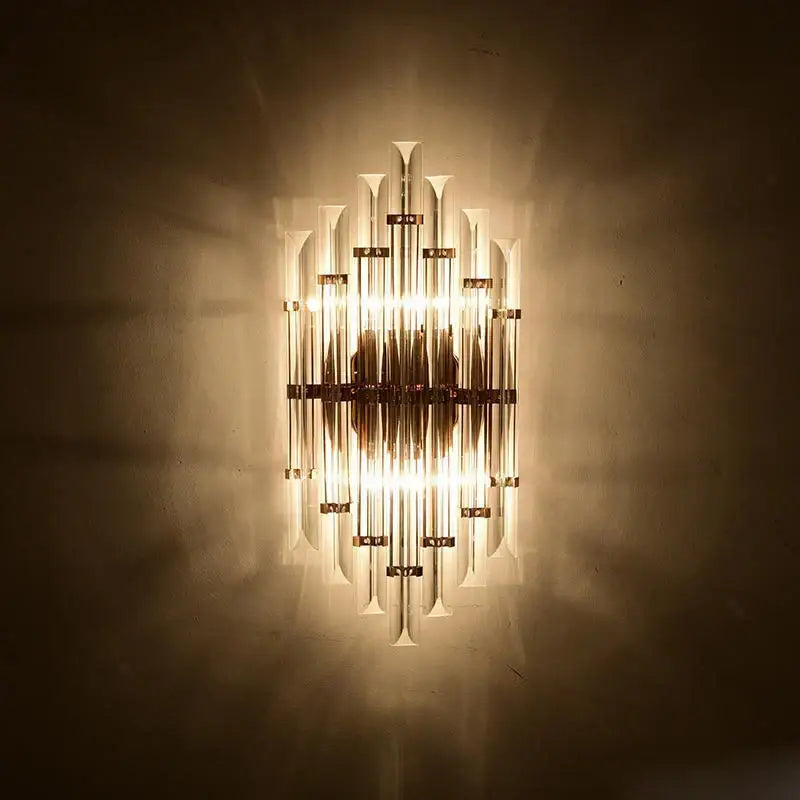 A warm glowing decorbites art deco led wall sconce with vertical glass tubes and brass finish for bedroom corridor lighting