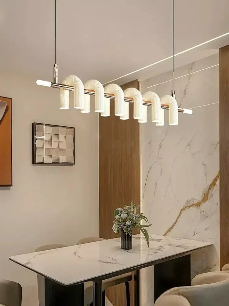 Modern white curved decorbites art deco pendant light with metallic accents above marble dining table