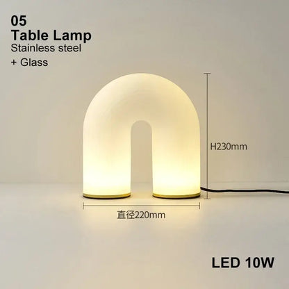 A modern decorbites art deco white acrylic u-shaped table lamp with warm diffused glow and stainless steel base