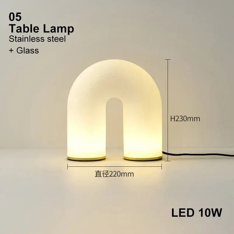 A modern decorbites art deco white acrylic u-shaped table lamp with warm diffused glow and stainless steel base