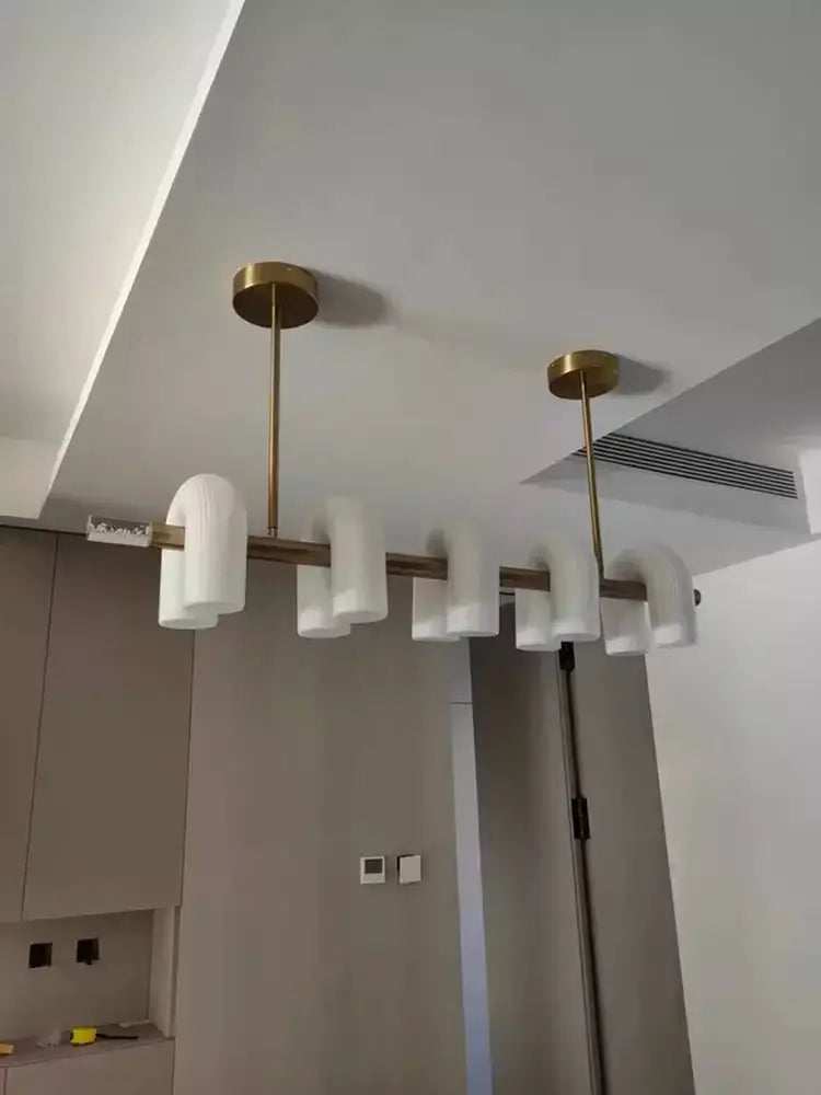Modern chandelier with brass finish and frosted white glass shades in a decorbites art deco white acrylic design