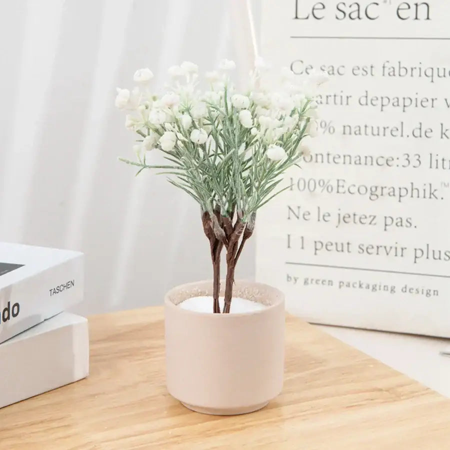 A delicate white artificial gypsophila plant arrangement with slender green stems in a blush ceramic pot for decor