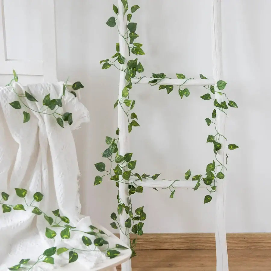 Decorbites artificial hanging green silk leaves garland draped over white ladder for christmas home decor