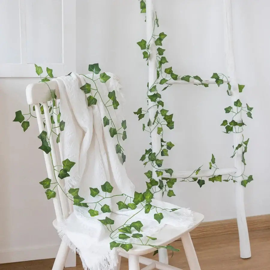 Decorbites artificial hanging green silk leaf garland draped over a white wooden chair for christmas decor