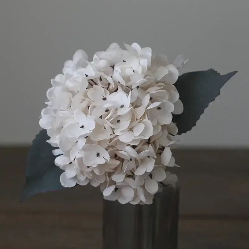 DecorBites artificial hydrangea silk flower arrangement with delicate white petals and dark green leaves in black vase
