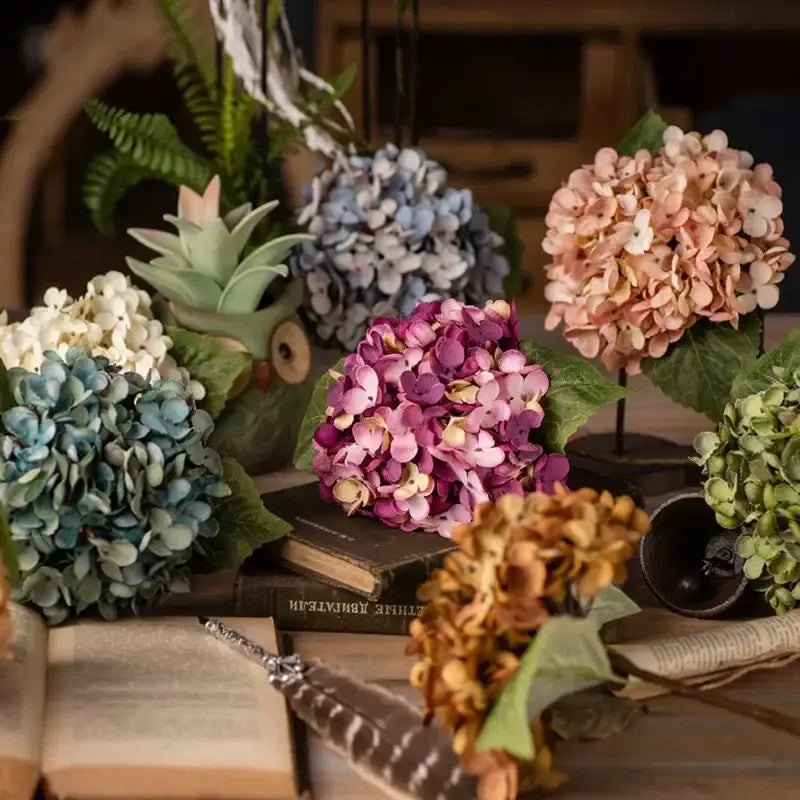 A decorbites artificial hydrangea silk flower arrangement in soft pink and purple hues with detailed green leaves for wedding decor